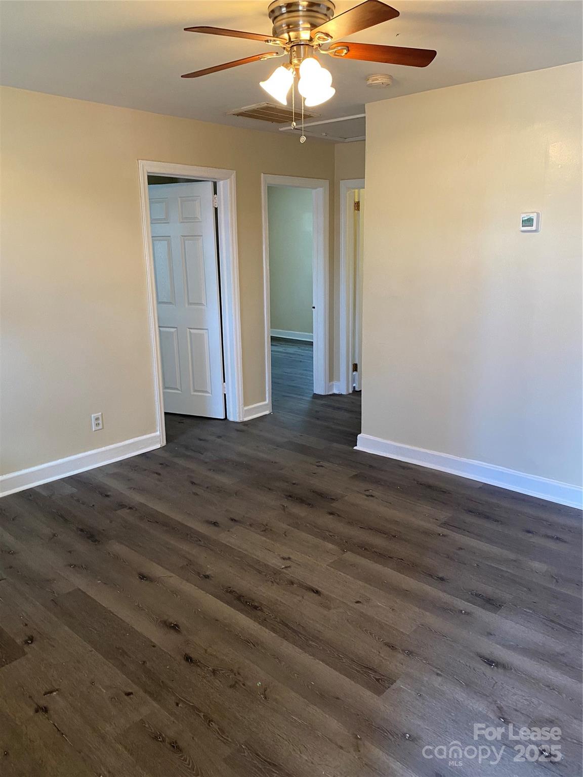 an empty room with wooden floor fan and window