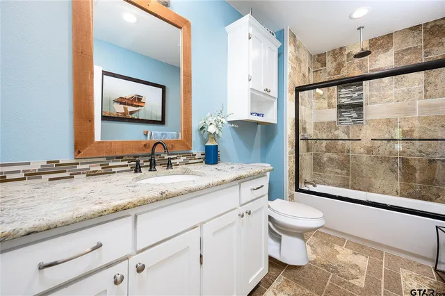 a bathroom with a granite countertop sink mirror vanity and toilet