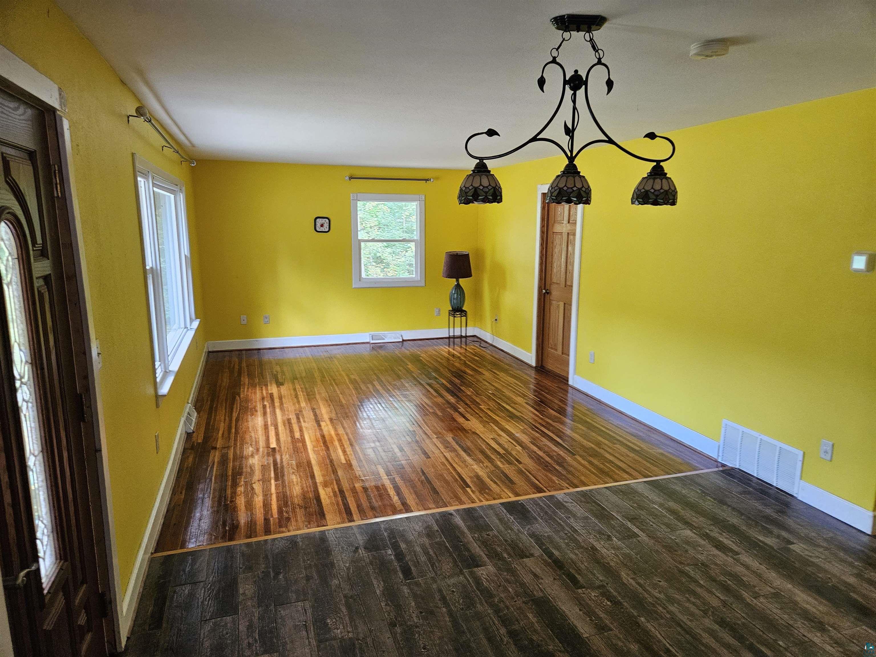 Empty room featuring a chandelier and dark hardwood / wood-style flooring