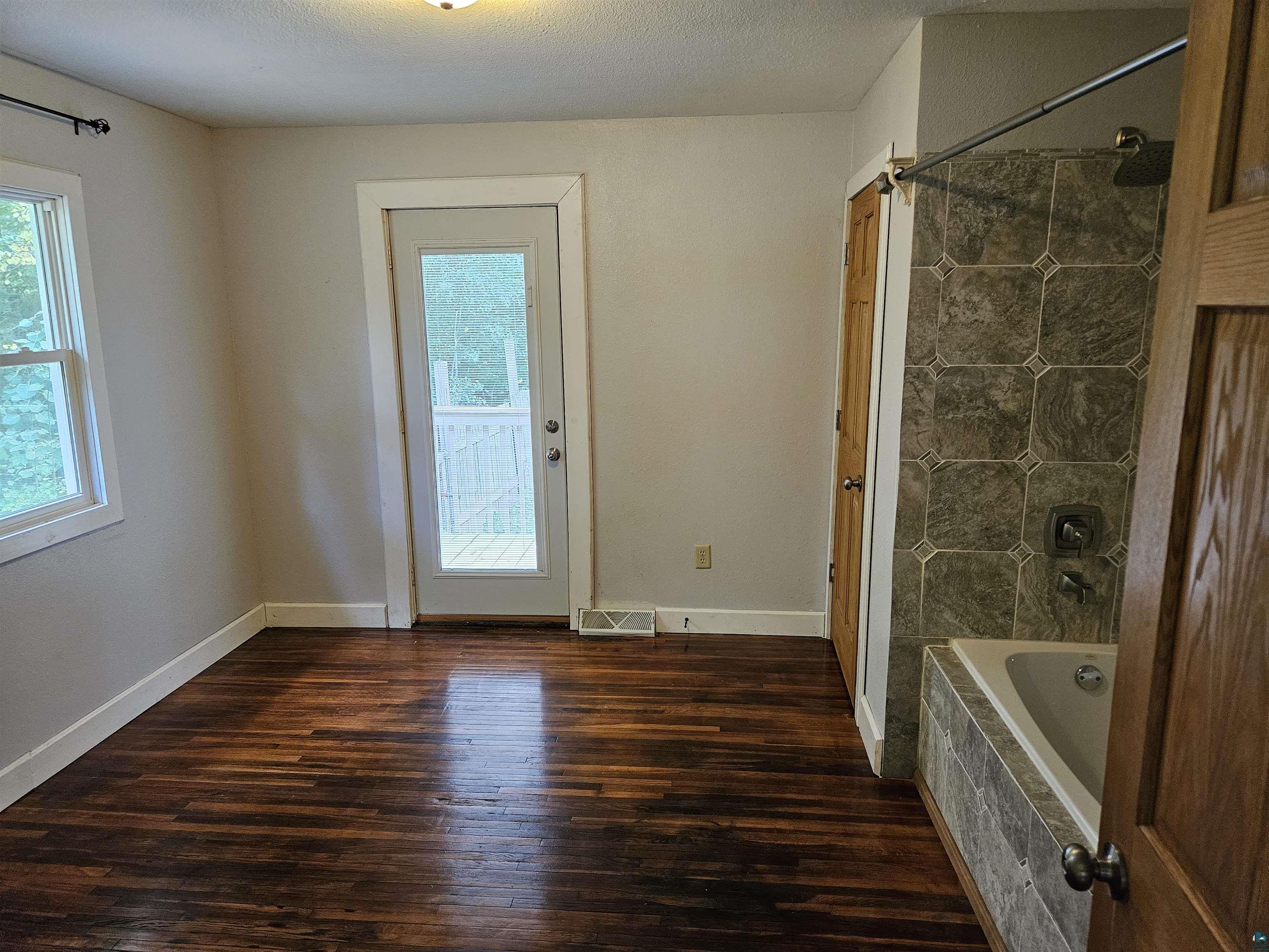 1534 Moorhead Road Cloquet, MN 55720 - Photo 8 of 16 Bathroom featuring a wealth of natural light, tiled shower / bath combo, hardwood / wood-style flooring, and a textured ceiling