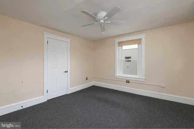 an empty room with a ceiling fan and window