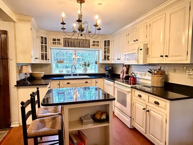 a kitchen with stainless steel appliances granite countertop a stove a sink dishwasher and white cabinets with wooden floor