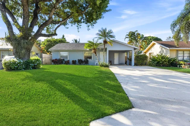 a front view of a house with a garden and trees