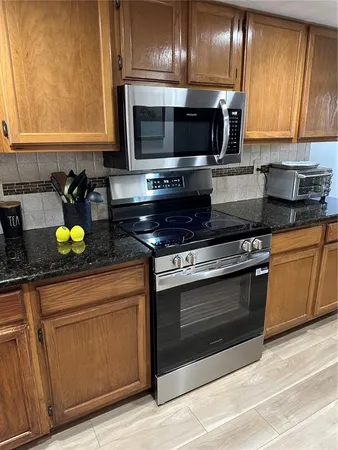 a kitchen with stainless steel appliances granite countertop a stove a microwave and wooden cabinets