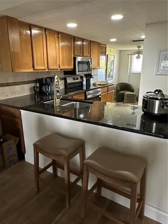 a kitchen with stainless steel appliances granite countertop a table chairs sink and wooden cabinets