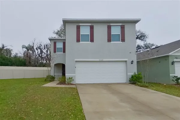 a front view of house with yard and trees in the background
