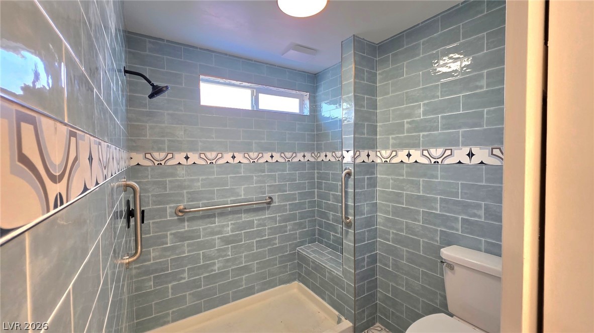 2155 Athol Way Laughlin, NV 89029 - Photo 9 of 19 A chic, walk-in shower features cool-toned subway tile, a decorative band, and a convenient built-in bench.