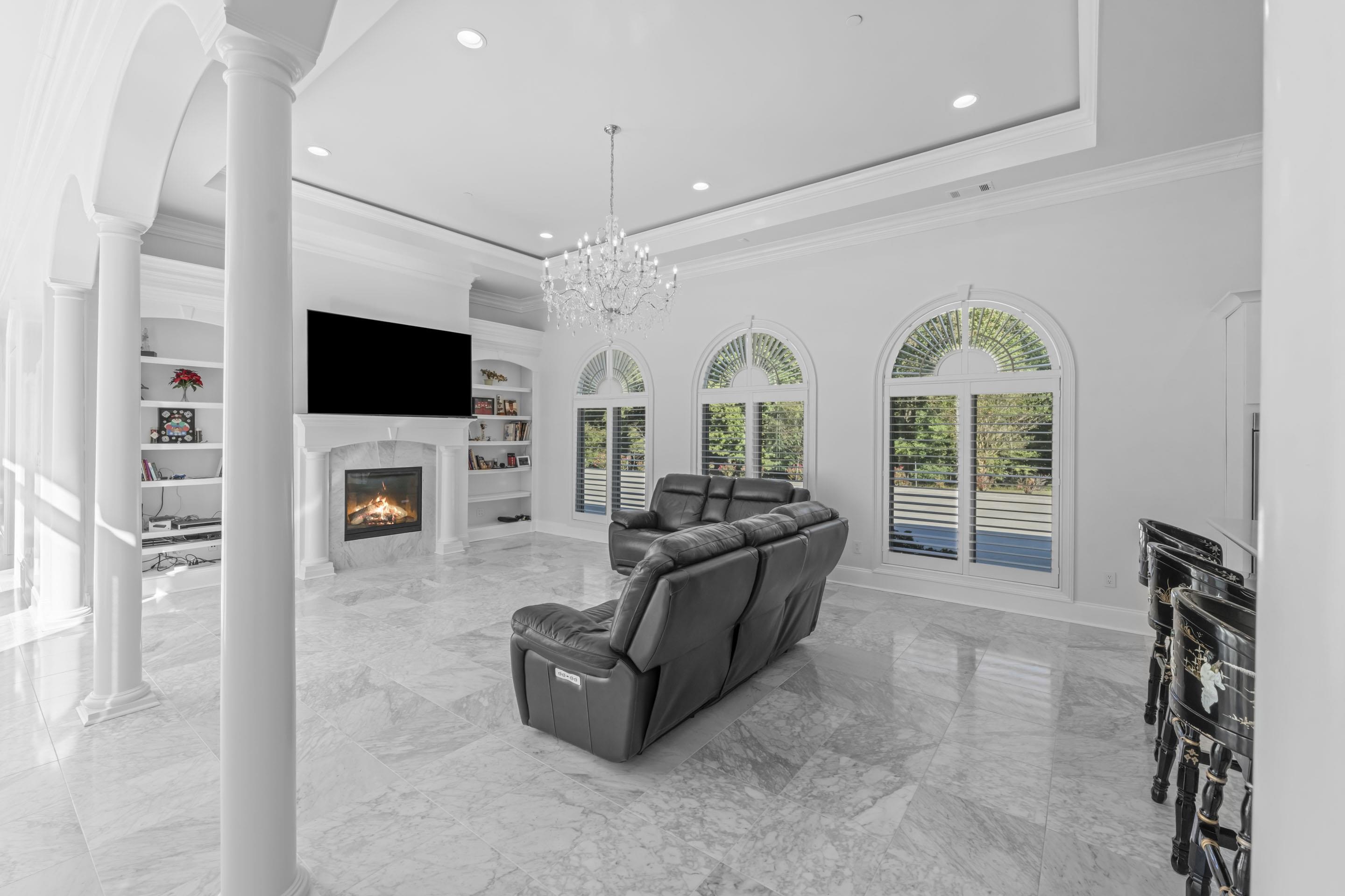 881 Bray Station Road Collierville, TN 38017 - Photo 10 of 40 Living room featuring light marble finish floors, crown molding, a raised ceiling, a high end fireplace, and built in shelves