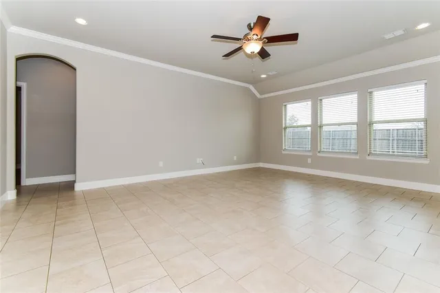 an empty room with chandelier fan and windows