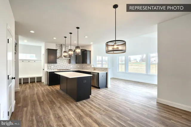 a large kitchen with kitchen island a stove a sink a center island and wooden floor