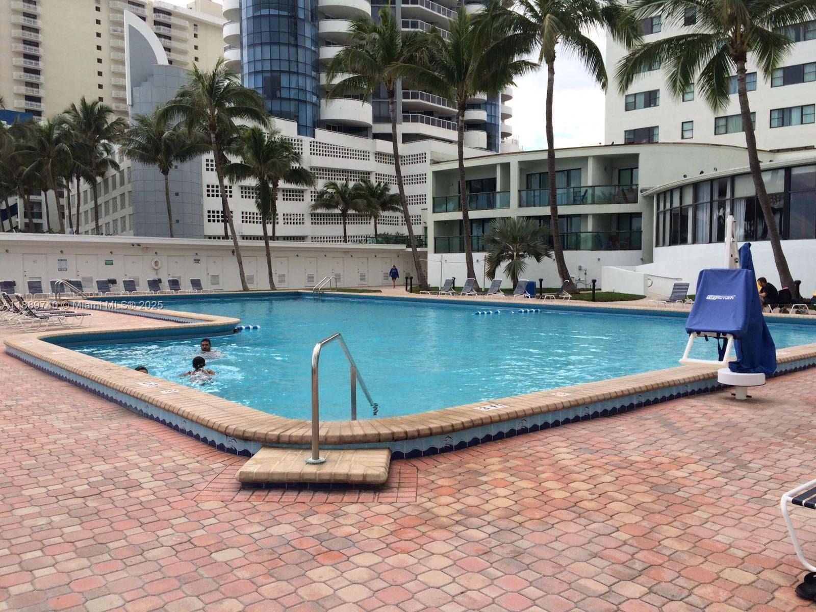 6345 Collins Avenue, Unit 937 Miami Beach, FL 33141 - Photo 22 of 27 a swimming pool with outdoor seating and yard