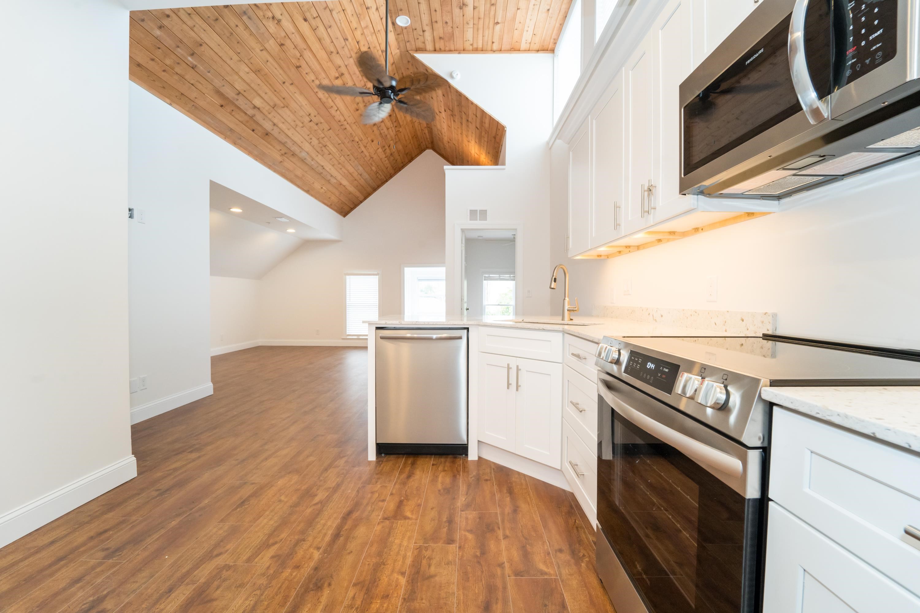 a kitchen view of a fireplace a ceiling fan and wooden floor