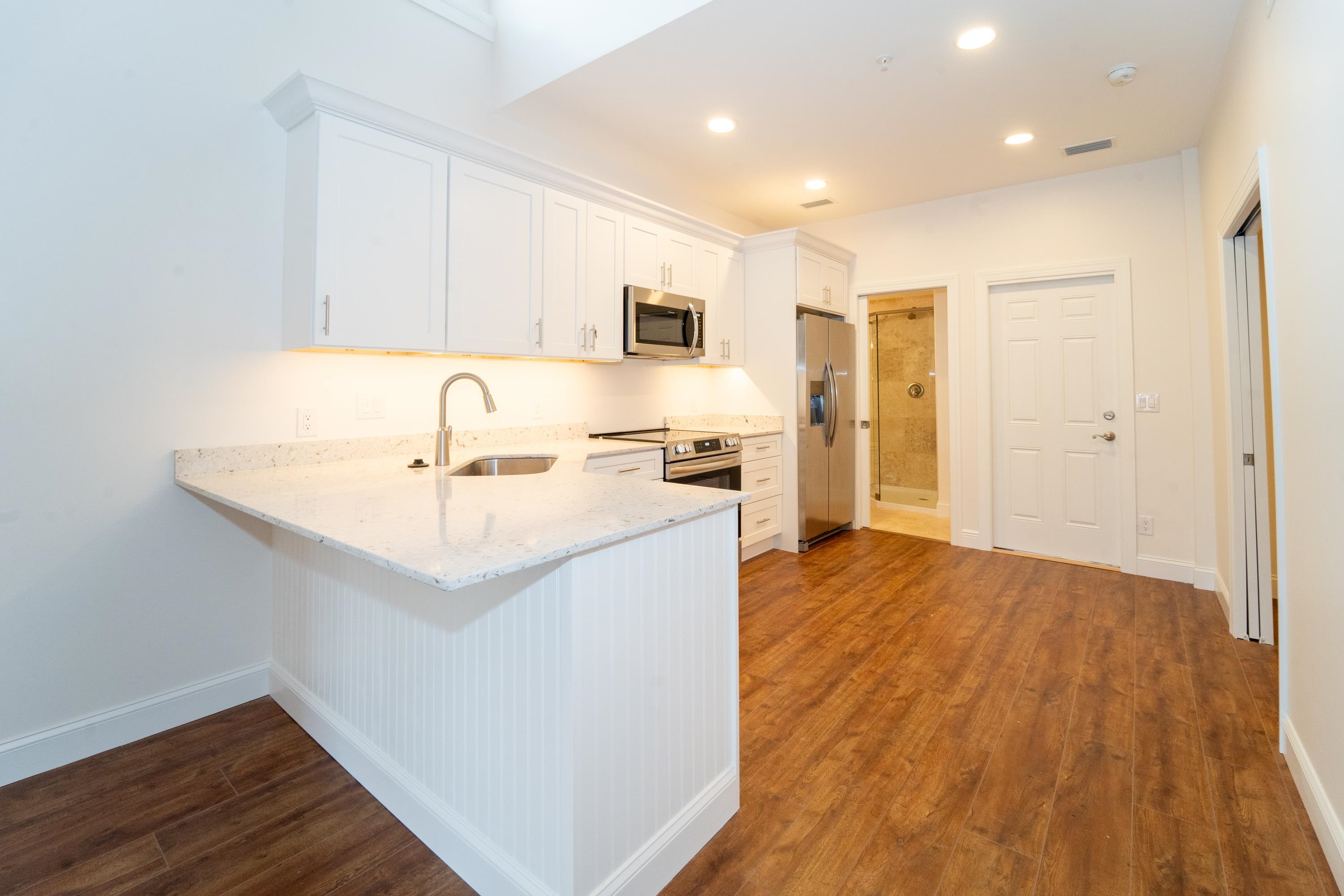 11 Aviles Street, Unit 3A St. Augustine, FL 32084 - Photo 16 of 17 a kitchen with a sink a refrigerator and wooden floor