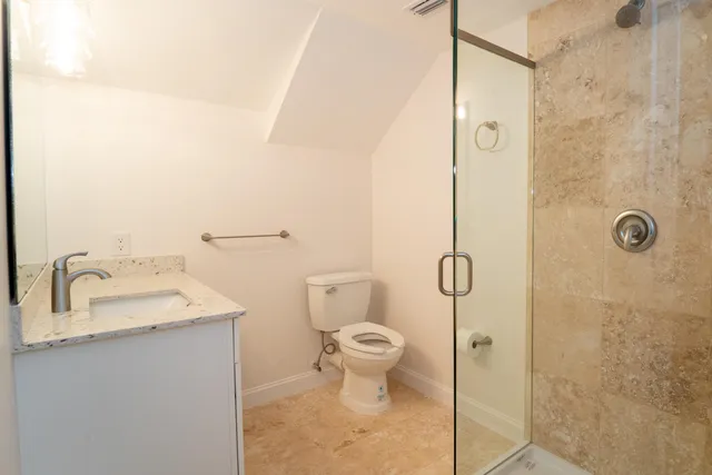 a bathroom with a granite countertop sink toilet and shower