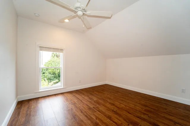 an empty room with wooden floor fan and windows