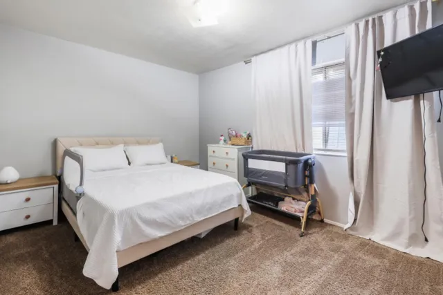 a bedroom with a bed a flat screen tv and dresser