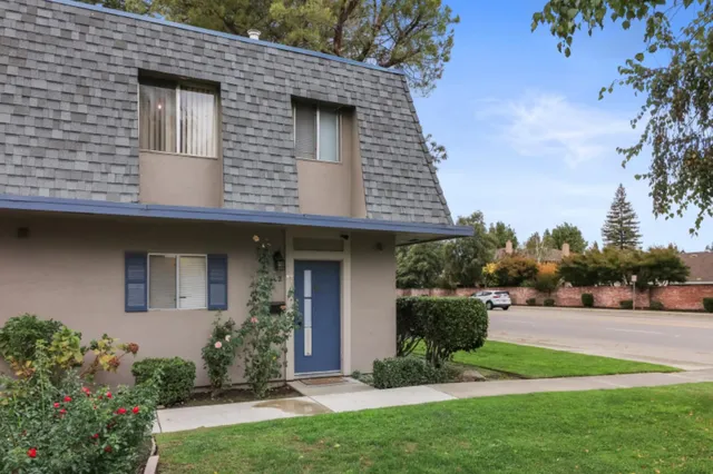 a front view of a house with a yard and potted plants
