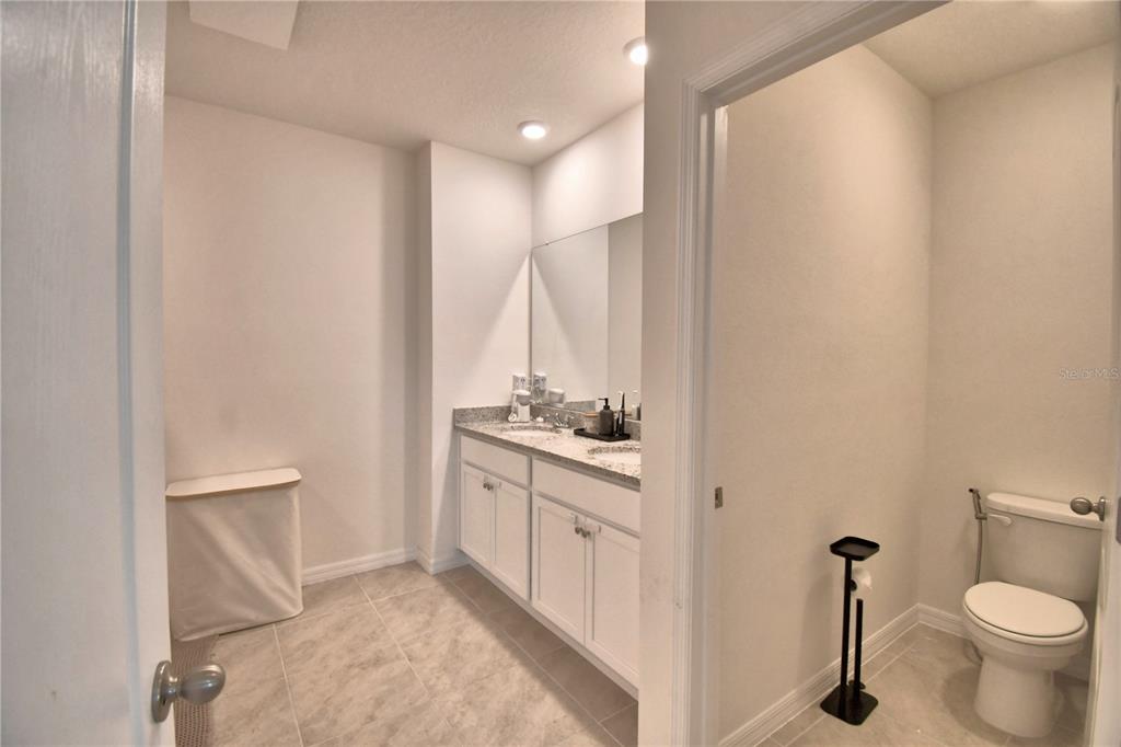 2839 Moulin Road Davenport, FL 33837 - Photo 35 of 75 a bathroom with a granite countertop sink a toilet and a mirror