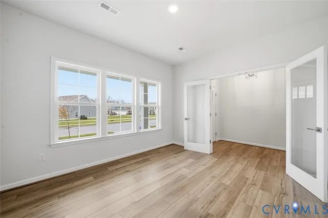 a view of an empty room with wooden floor and a window