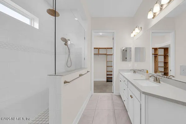 a spacious bathroom with a double vanity sink a mirror and a shower