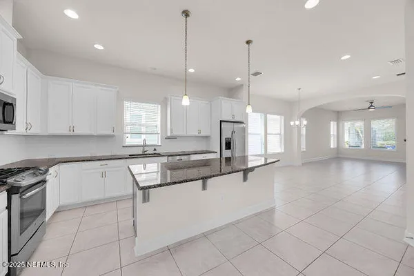 a large kitchen with stainless steel appliances granite countertop a sink a stove and a refrigerator