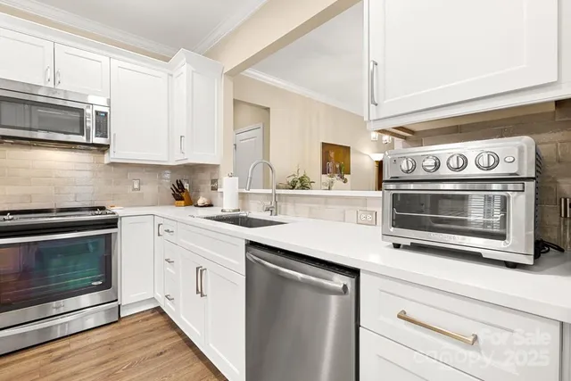 a kitchen with stainless steel appliances white cabinets and a stove top oven