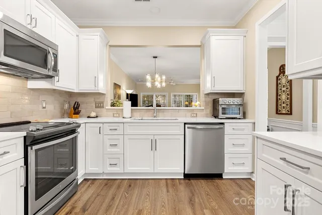 a kitchen with stainless steel appliances granite countertop a stove a sink and white cabinets