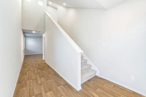 a view of a hallway with wooden floor and staircase