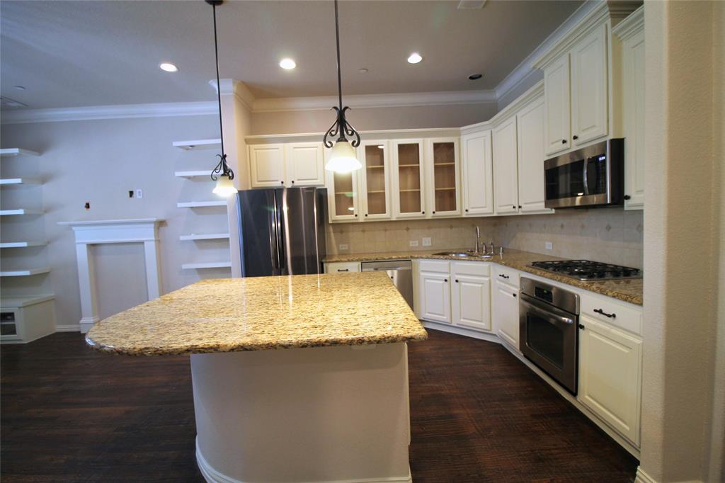 528 Tuscan Drive Irving, TX 75039 - Photo 14 of 40 Kitchen featuring a kitchen island, glass insert cabinets, ornamental molding, light stone counters, and decorative light fixtures
