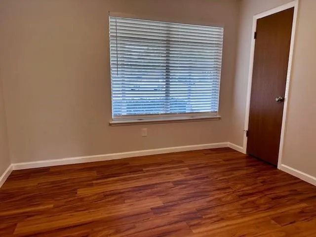 an empty room with wooden floor and a window