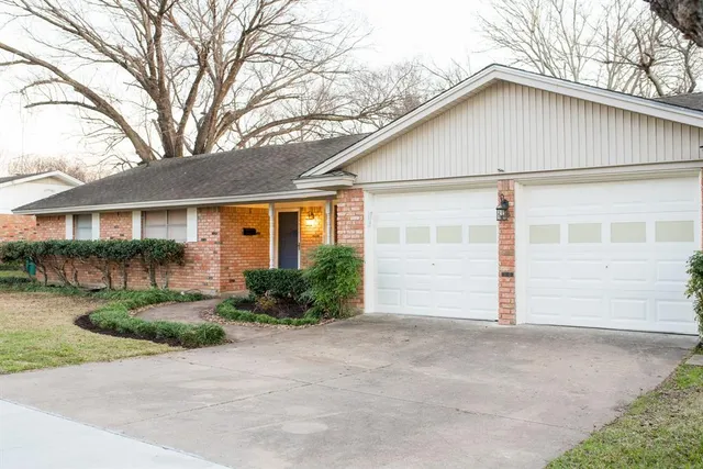 a view of a white house with a large window and potted plants