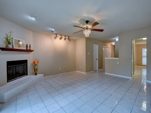 a view of a livingroom with a ceiling fan a fireplace and a chandelier fan