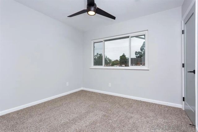 an empty room with a window and a ceiling fan