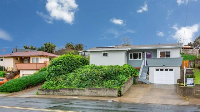 a front view of a house with a yard and potted plants