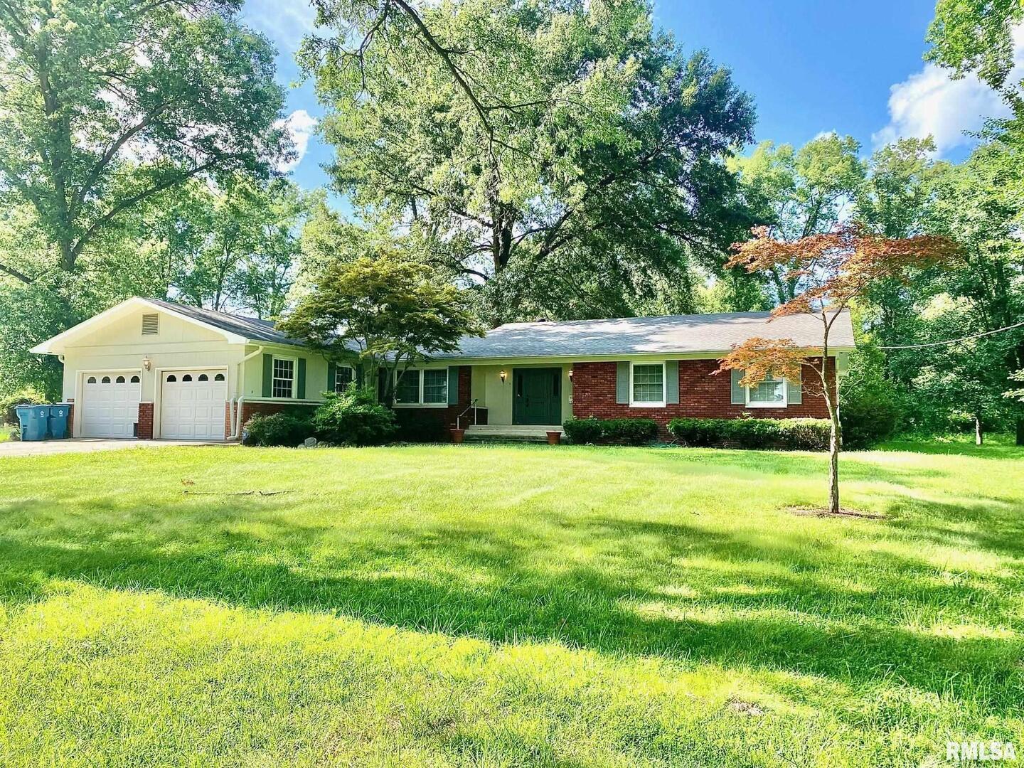 a front view of a house with a yard and trees