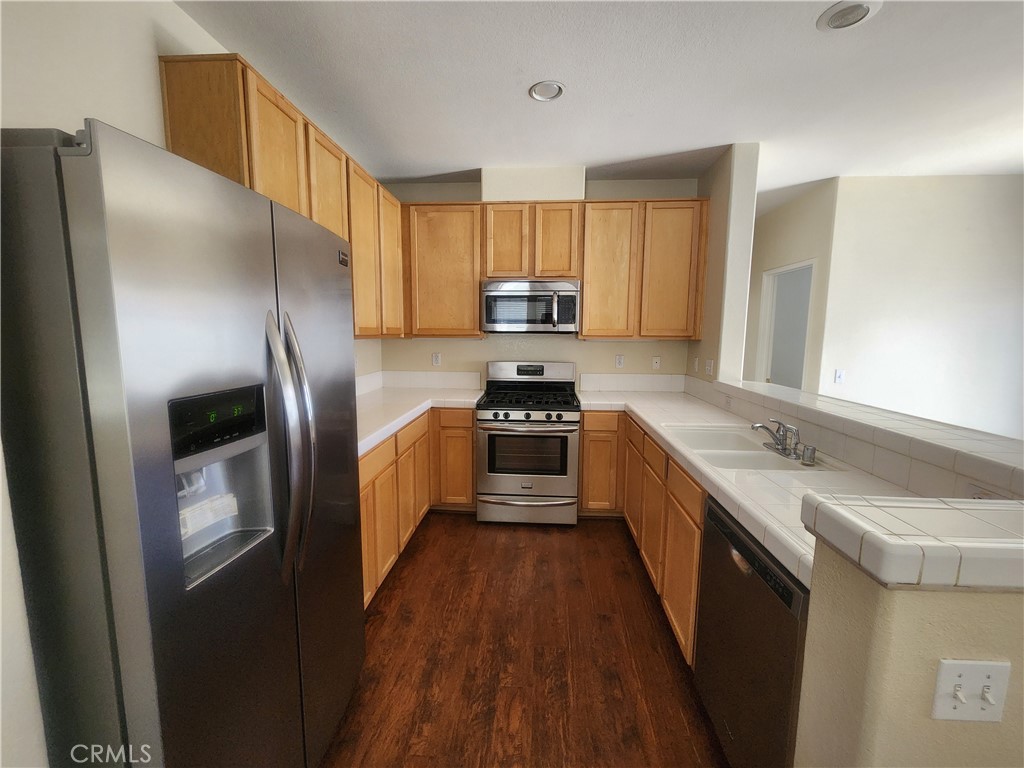 7331 Shelby Place, Unit U43 Rancho Cucamonga, CA 91739 - Photo 10 of 26 a kitchen with stainless steel appliances a refrigerator sink and wooden cabinets