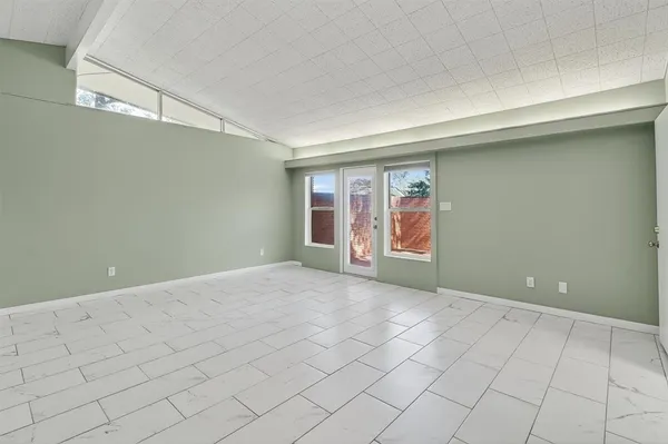a view of an empty room with window and chandelier