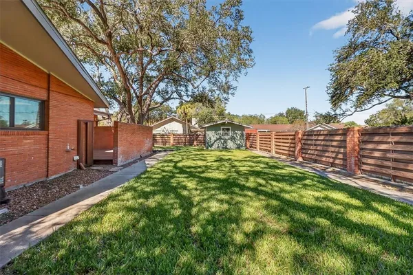 a view of a backyard with brick wall and large trees