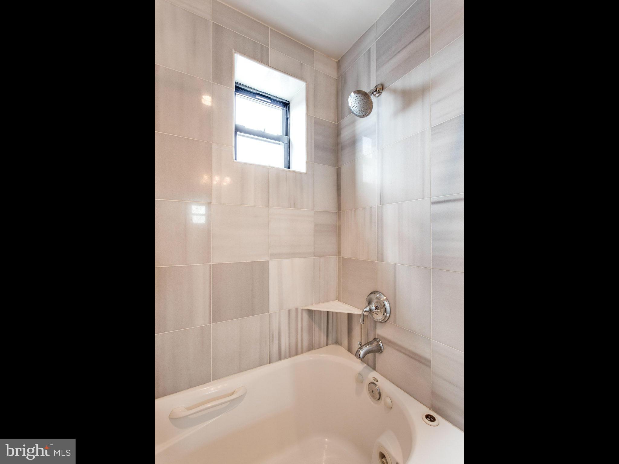 1354 Euclid Street Northwest, Unit B402 Washington, DC 20009 - Photo 16 of 30 a bathroom with a tub sink and mirror