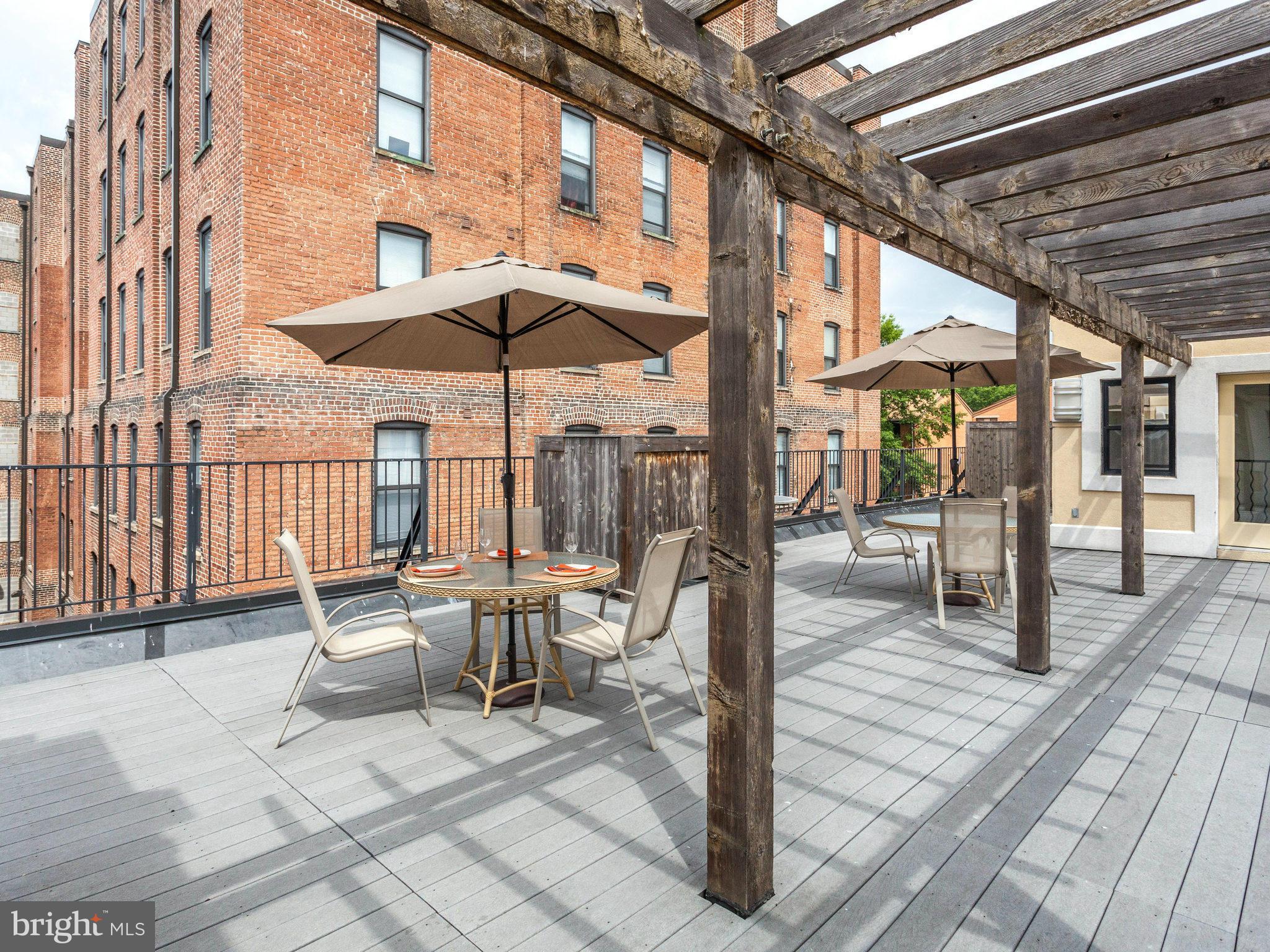 1354 Euclid Street Northwest, Unit B402 Washington, DC 20009 - Photo 28 of 30 a view of a patio with a table and chairs under an umbrella with a barbeque