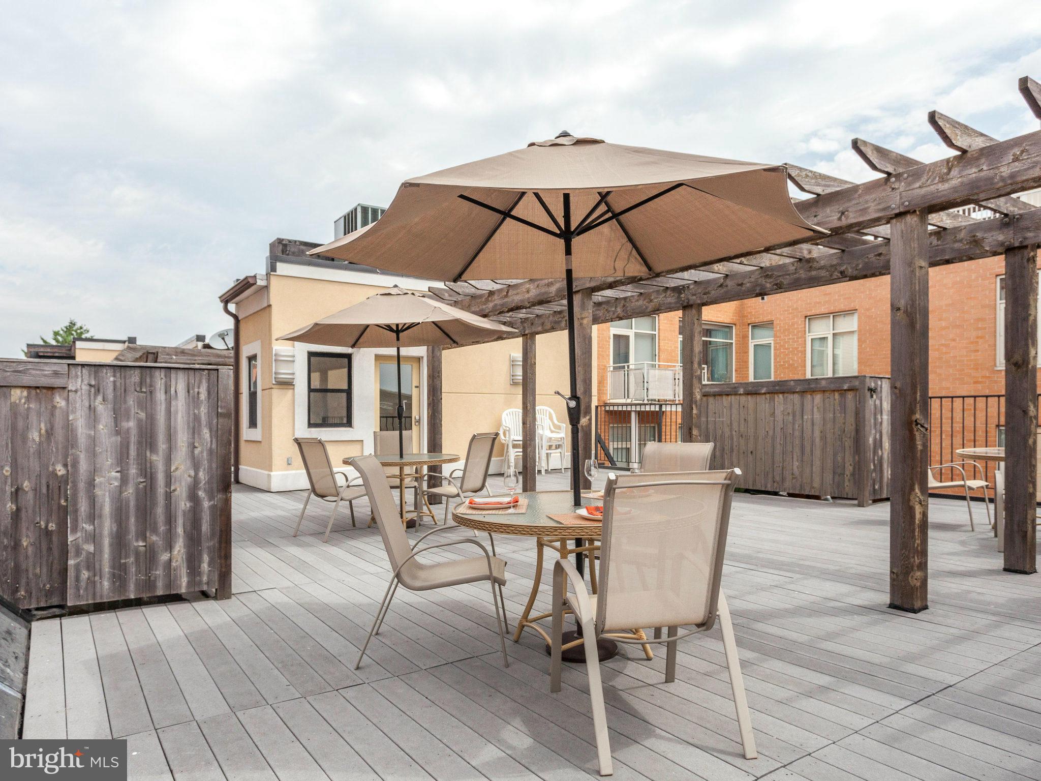 1354 Euclid Street Northwest, Unit B402 Washington, DC 20009 - Photo 29 of 30 a view of a roof deck with table and chairs under an umbrella with wooden floor
