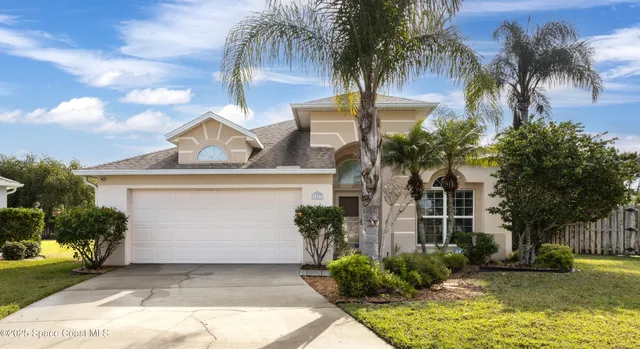 front view of house with a yard and palm trees