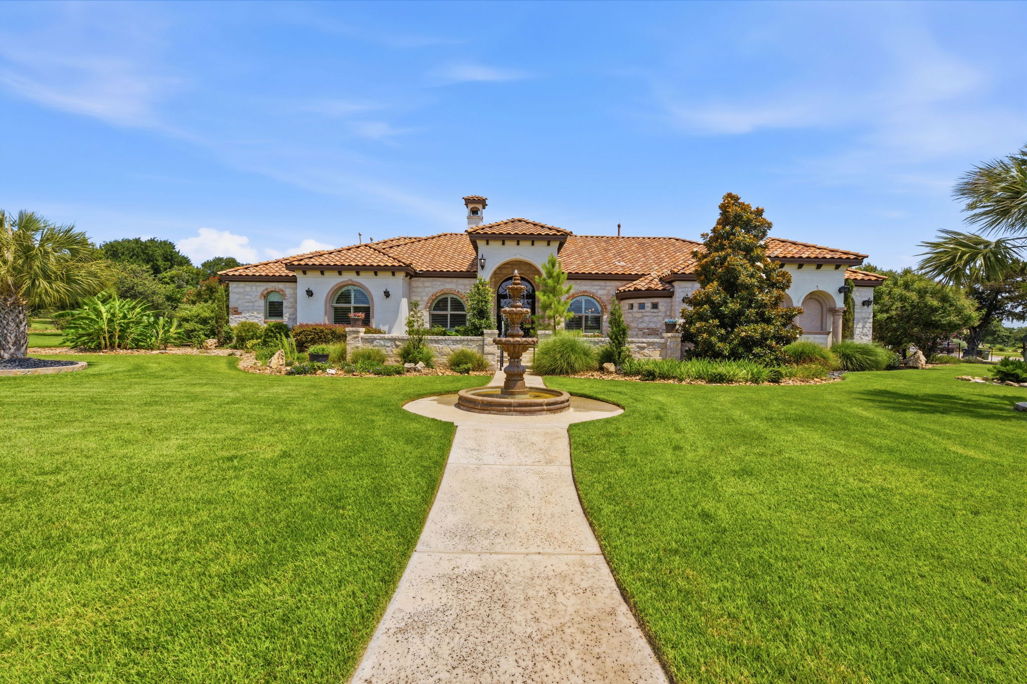 Grand Mediterranean-inspired residence awaits with a captivating front fountain and lush, manicured grounds.
