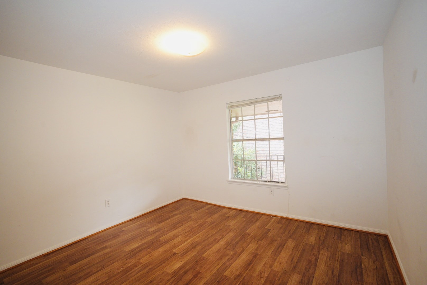 7600 Burgoyne Road, Unit 250 Houston, TX 77063 - Photo 5 of 14 This inviting second bedroom features warm wood flooring and ample natural light, creating a cozy and versatile space perfect for relaxation or productivity.