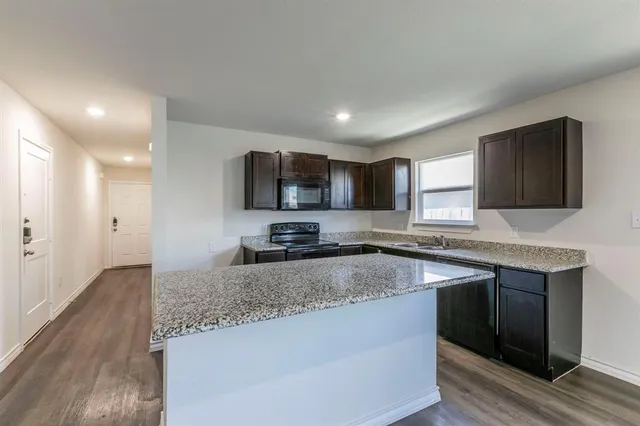 a kitchen with granite countertop a sink and a stove top oven