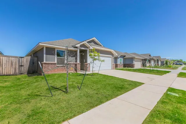 a front view of a house with a yard and potted plants