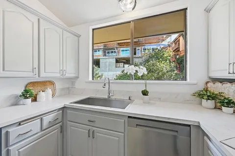 a kitchen with stainless steel appliances white cabinets and a window