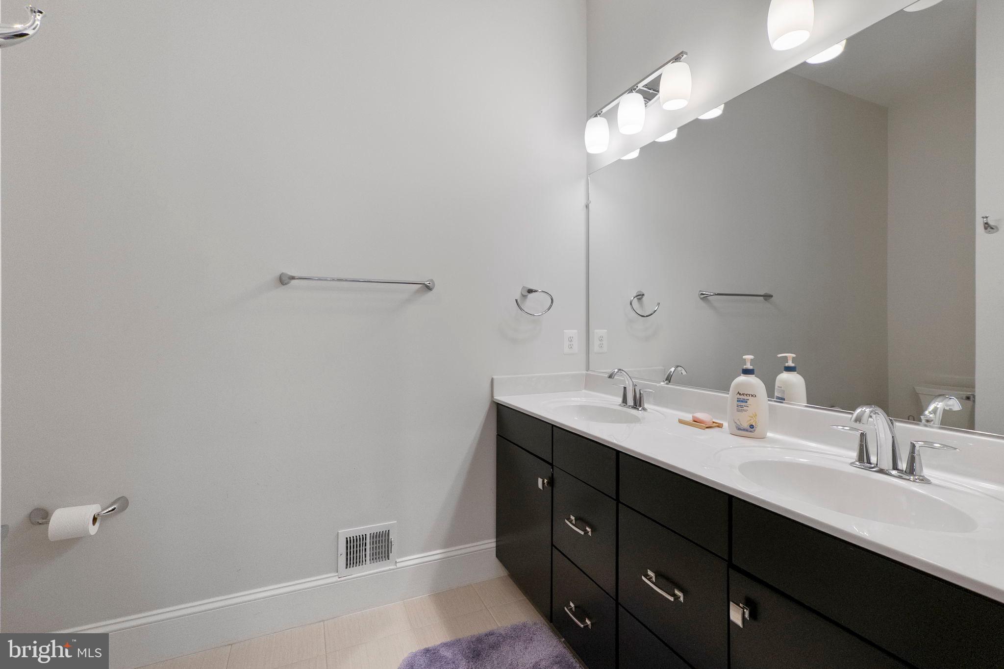 11760 Glen Mill Road Potomac, MD 20854 - Photo 23 of 64 a bathroom with a double vanity sink and a mirror
