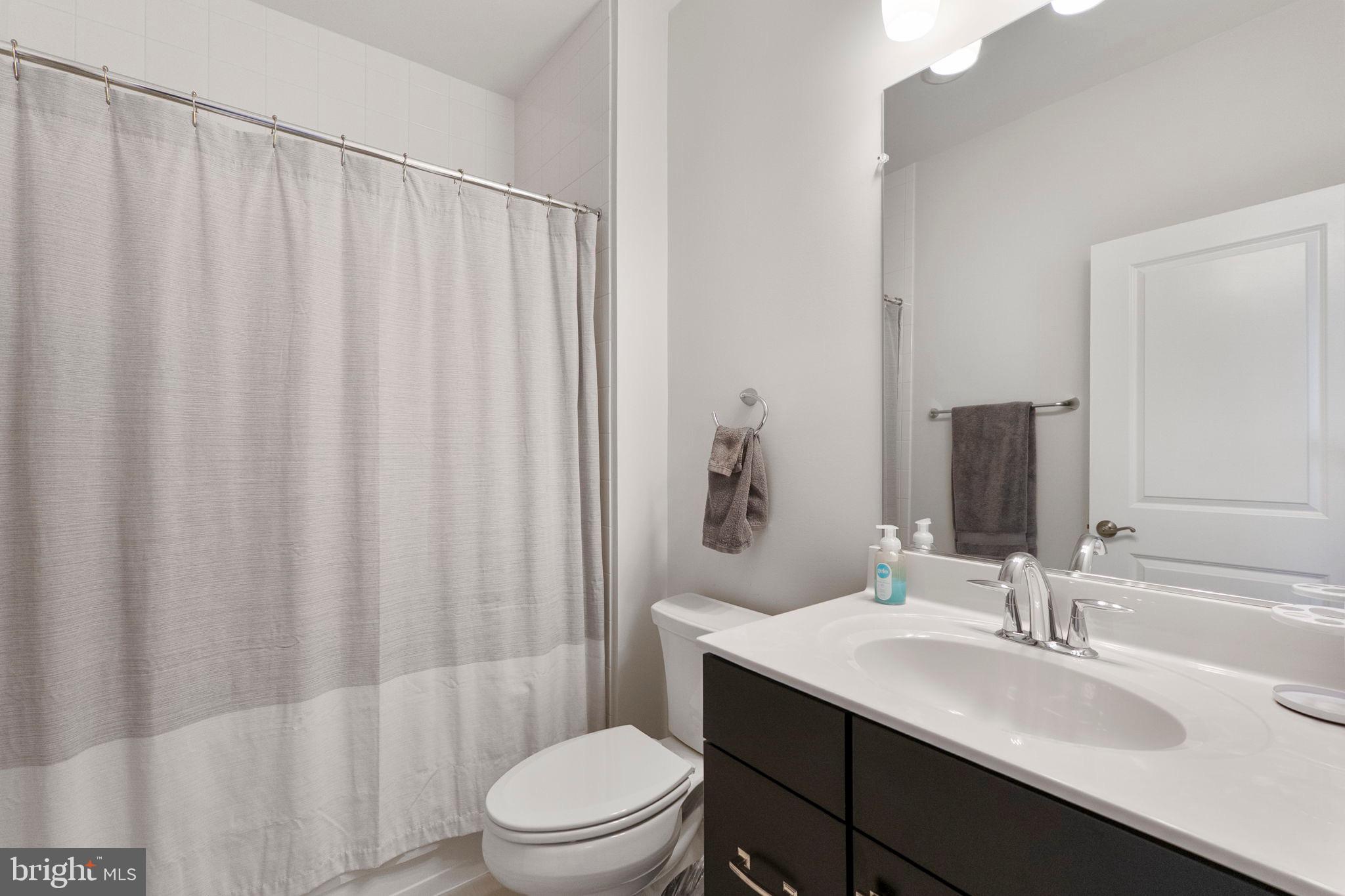 11760 Glen Mill Road Potomac, MD 20854 - Photo 37 of 64 a bathroom with a sink a toilet a mirror and shower curtain