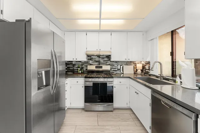 a kitchen with stainless steel appliances granite countertop a stove a sink and a refrigerator